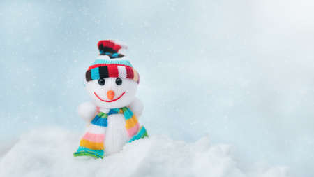 Merry christmas and happy new year greeting card with copy space. Happy Toy of snowman in cap and scarf standing in winter snow background. christmas fairytale.の写真素材