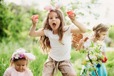 Easter egg hunt. Group Of Children Wearing Bunny Ears Running To Pick Up colorful Egg On Easter Egg...