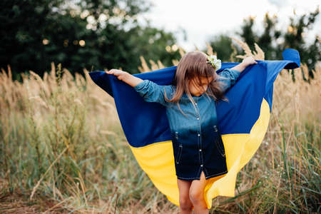 Ukraines Independence Flag Day. Constitution day. Ukrainian child girl in embroidered shirt vyshyvanka with yellow and blue flag of Ukraine in field. flag symbols of Ukraine. Kyiv, Kiev dayの写真素材