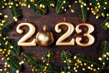 Holiday background Happy New Year 2023. Numbers of year 2023 made by gold candles wooden rustic background with fir tree. celebrating New Year holiday, close-up. Space for textの写真素材