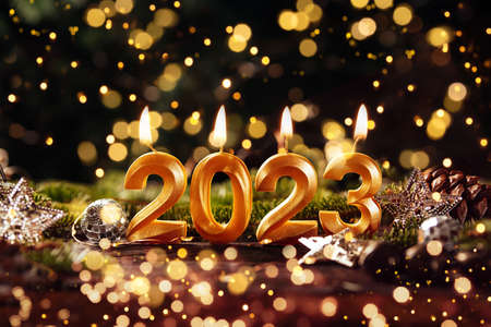 Holiday background Happy New Year 2023. Numbers of year 2023 made by gold burning candles on bokeh...