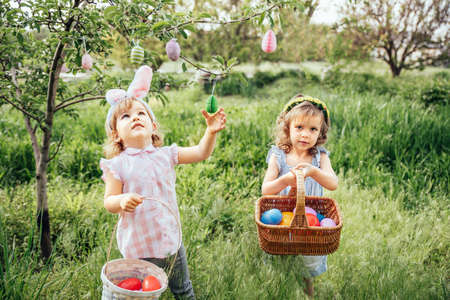 Easter egg hunt. Group Of Children Wearing Bunny Ears Running To Pick Up colorful Egg On Easter Egg Hunt In Garden. Easter traditionの写真素材