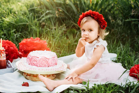 second birthday of little girl. Two years old girl sitting near celebration decorations and eating her birthday cake. Cake Smashの写真素材