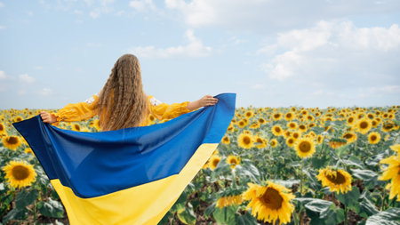 Girl carries fluttering blue and yellow flag of Ukraine in sunflower field. Pray for Ukraine. Little girl waving national flag praying for peace. 24 August. unity, support. Ukrainians are against war.の写真素材