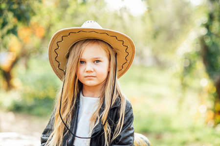 portrait of girl in cowboy hat in autumn park. Children and Ecology. Healthy nutrition Garden Food.の写真素材