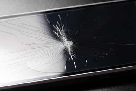 Broken glass background with bullet hole over black background. Shattered and broken glass pieces...