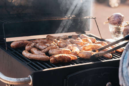 Grilled sausages or bratwurst on grill with smoke and flame. Delicious german sausages on barbecue...