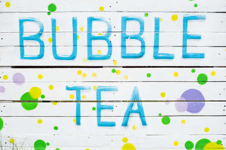 Text in English Bubble tea on white wooden plank background. Food and catering concept. invitation cafe marketing promotion. Cafe in Garden sign outside restaurantの写真素材