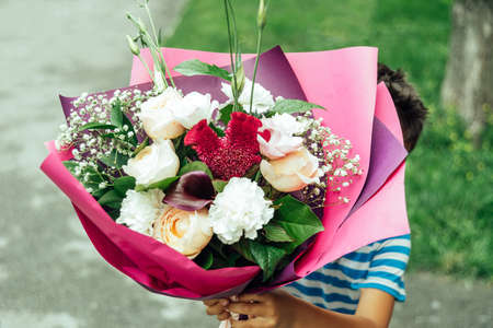Cute little boy holding bouquet of flowers for Mom outside. Mothers Day. International Women day. happy birthdayの写真素材