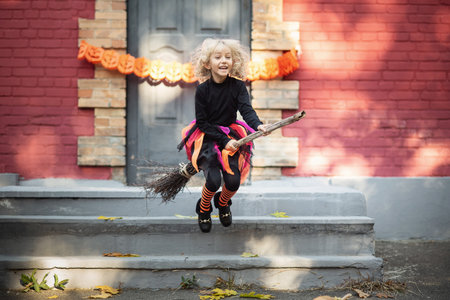 Beautiful girl witch. little girl in witch costume celebrate Halloween outdoor and have fun. Kids trick or treatingの写真素材