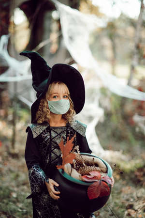 Happy Halloween on quarantine pandemic. social distance. Child Girl in witch Halloween costume wearing medicine mask. Kids trick or treating. Child safety.の写真素材