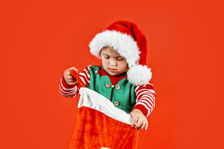 Happy child with Down syndrome in Christmas scarf having fun and laughing in studio. Christmas mood. happy new year. Portrait on red backgroundの写真素材