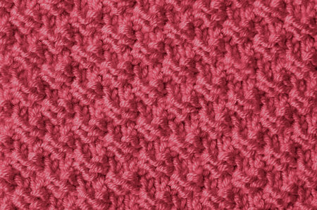Trendy color of 2023 viva magenta. Knit texture of magenta wool knitted fabric with pattern...