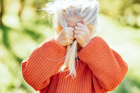 Portrait of sweet little blonde girl playing in sun outdoors. Happy little child having fun at park. Laughing child. Expressive facial with cute expression.の写真素材