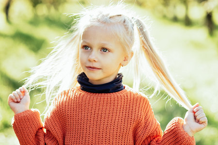 Portrait of sweet little blonde girl playing in sun outdoors. Happy little child having fun at park. Laughing child. Expressive facial with cute expression.の写真素材
