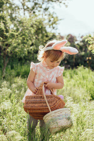 Easter egg hunt. Girl child Wearing Bunny Ears Running To Pick Up Egg In Garden. Easter tradition....