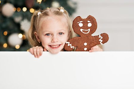 Merry Christmas and Happy Holidays. Child girl with sheet of blank paper under Christmas tree Waiting for Christmas. Celebration New Year. Mockup poster advertisement, sale greeting card concept.の写真素材