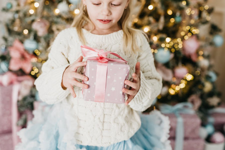 Merry Christmas and Happy Holidays. Little child under Christmas tree. baby girl with gift under Christmas tree with many gift boxes presents. Celebration New Year.の写真素材