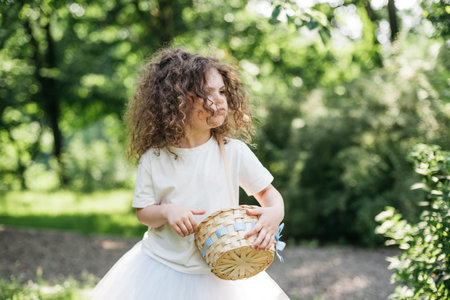 Easter egg hunt. Girl child Wearing Bunny Ears Running To Pick Up Egg In Garden. Easter tradition. Baby with basket full of colorful eggs.の写真素材