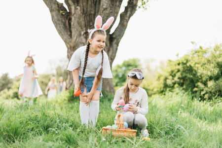 Easter egg hunt. Group Of Children Wearing Bunny Ears Running To Pick Up colorful Egg On Easter Egg Hunt In Garden. Easter traditionの写真素材