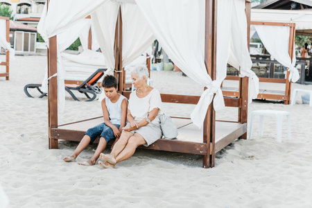 summer vacation at sea. Boy and senior woman at seaside. Grandmother with grandchild are resting on sea, running on beach having fun at summer holiday. Active people activity with children.の写真素材