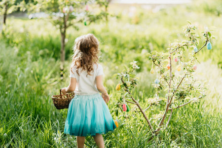 Easter egg hunt. Girl child Wearing Bunny Ears Running To Pick Up Egg In Garden. Easter tradition....