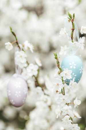Easter Greeting Card. Easter eggs hanging on blossoming tree branches with white spring flowers and green blurred backgroundの写真素材