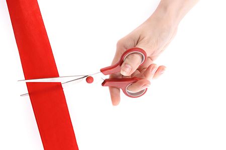 Red ribbon, scissors and hand isolated on white