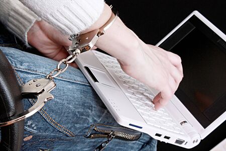 Hand in handcuffs on laptopの写真素材