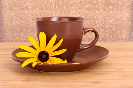 Cup of green tea on the saucer with yellow flowerの写真素材