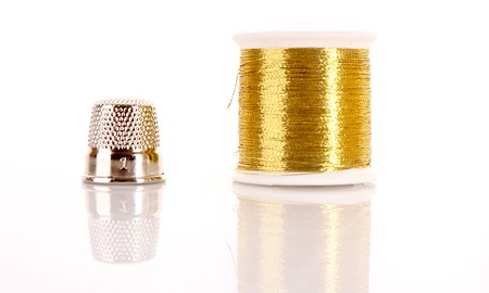 Golden thread and thimble isolated on whiteの写真素材