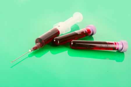 Medical test tubes and syringe with blood on greenの写真素材