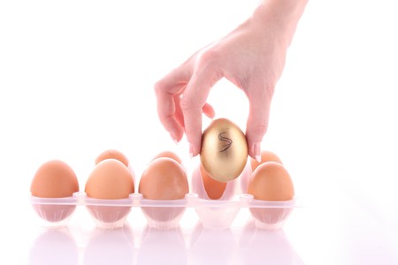 Gold and simple egg in hands isolated on whiteの写真素材