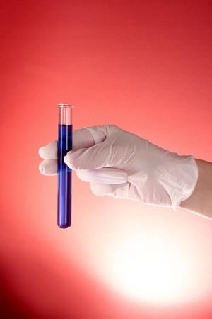 test tube in hand over red backgroundの写真素材