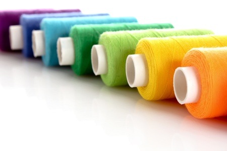 Pile of coloured bobbins of lurex thread isolated on white