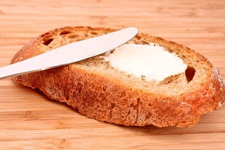 knife and a bread with butter on a wooden stand