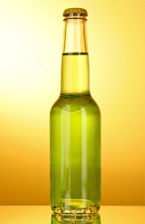 Bottle with a green alcoholic beverage on a yellow backgroundの写真素材