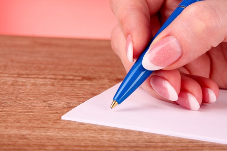 pen in hand writing on paper
