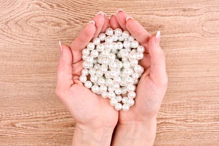 Woman hand with pearls on wooden backgroundの写真素材