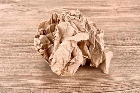 Brown crumpled paper ball on wooden textureの写真素材