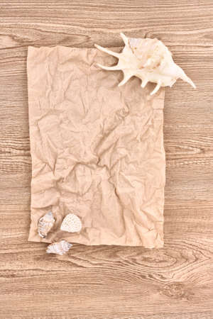 Brown crumpled paper with seashells on wooden textureの写真素材