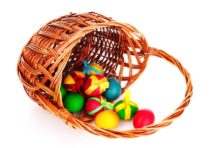 Wicker basket with Easter eggs isolated on whiteの写真素材