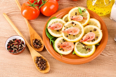 Shrimp on lemons with tomato, peppers and oil on wooden tableの写真素材