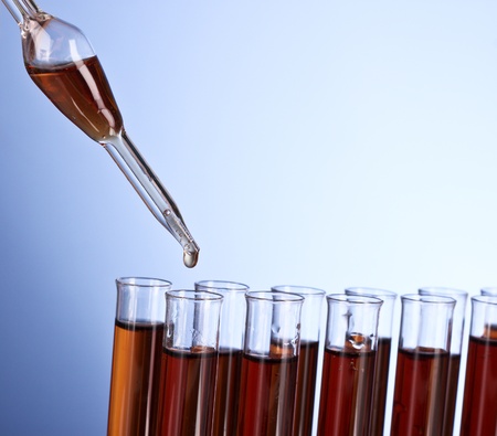 Test tubes closeup on blue background. Drops from test stickの写真素材