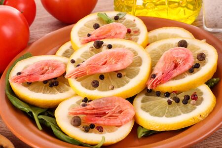 Shrimp on lemons with tomato, peppers and oil on wooden tableの写真素材