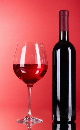 Wine bottle and glass on red backgroundの写真素材