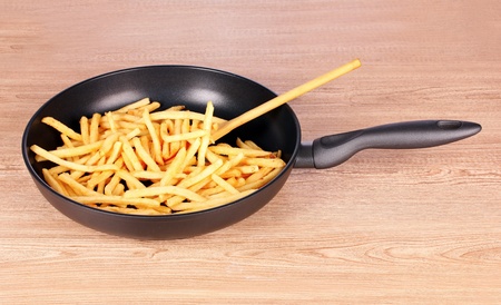 French fries in the pan on a wooden backgroundの写真素材