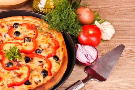 tasty pizza with olives and vegetables on a wooden backgroundの写真素材