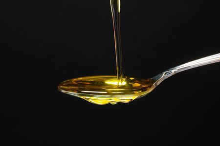 olive oil in spoon on black background
