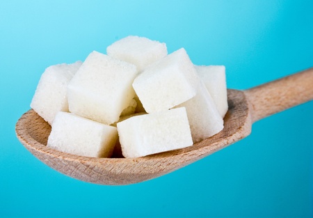 refined sugar in wooden spoon on blue backgroundの写真素材